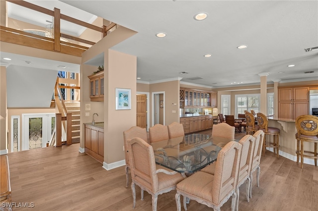 dining room with light wood-style flooring, decorative columns, crown molding, and french doors