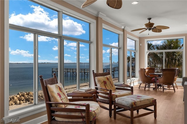 sunroom with a ceiling fan, a wealth of natural light, and a water view