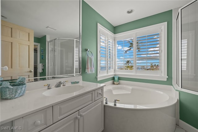 bathroom with a stall shower, vanity, and a bath