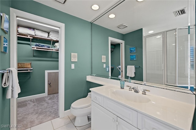 bathroom featuring tile patterned flooring, toilet, vanity, visible vents, and a walk in closet