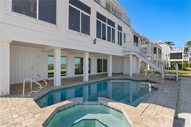 view of swimming pool featuring a pool with connected hot tub, a patio area, and stairs