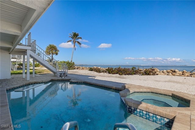 view of swimming pool featuring a water view, a pool with connected hot tub, and stairs