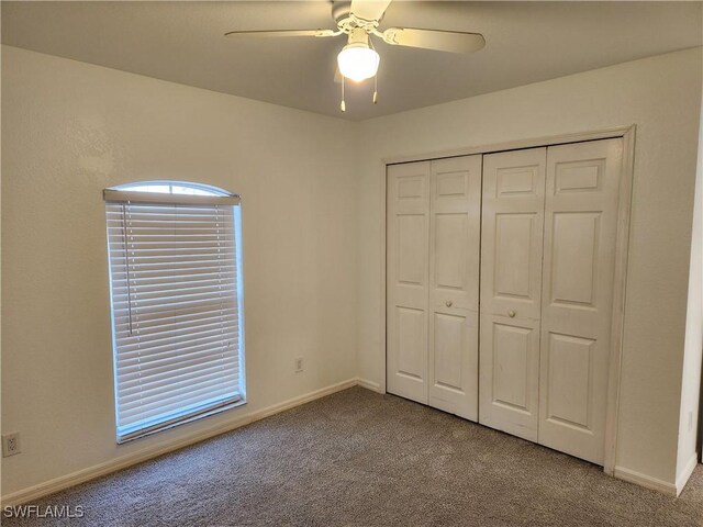 unfurnished bedroom featuring a ceiling fan, a closet, baseboards, and carpet flooring