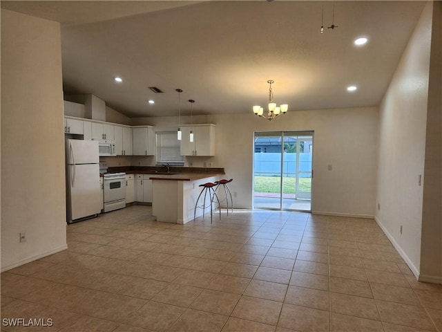 kitchen with white appliances, dark countertops, open floor plan, a kitchen breakfast bar, and a peninsula