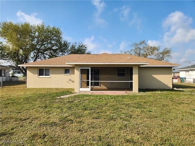 rear view of property featuring a sunroom, a lawn, fence, and stucco siding