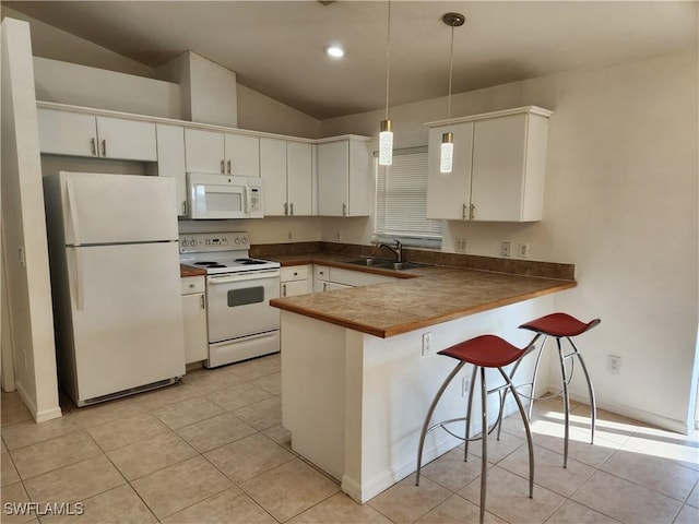 kitchen featuring pendant lighting, dark countertops, a sink, white appliances, and a peninsula