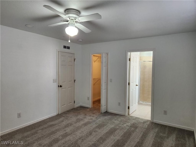 unfurnished bedroom with baseboards, visible vents, ensuite bath, a walk in closet, and carpet floors