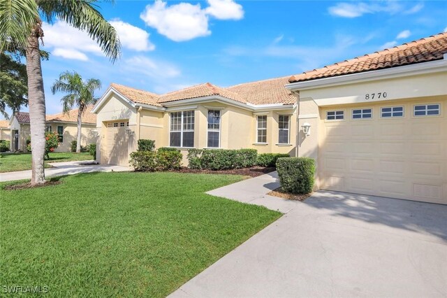 mediterranean / spanish-style home with a garage, concrete driveway, a front lawn, and stucco siding