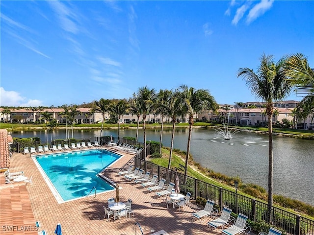 pool featuring a residential view, a water view, fence, and a patio