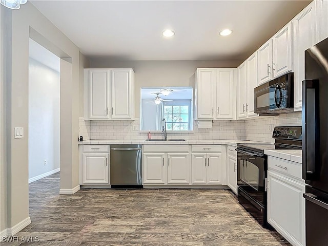 kitchen with black appliances, a sink, white cabinets, and decorative backsplash