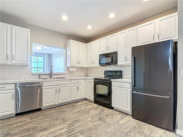 kitchen featuring white cabinetry, a sink, light wood-style flooring, and black appliances