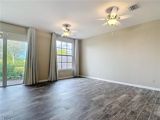 unfurnished room featuring dark wood-type flooring, a ceiling fan, visible vents, and baseboards