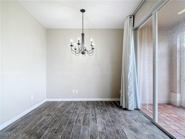 empty room featuring dark wood finished floors, baseboards, and an inviting chandelier