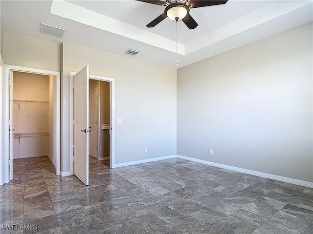 unfurnished bedroom with a tray ceiling, visible vents, and baseboards