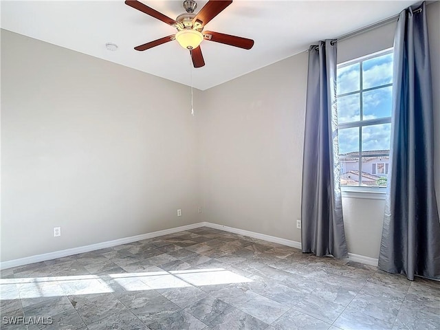 unfurnished room featuring stone finish floor, ceiling fan, and baseboards