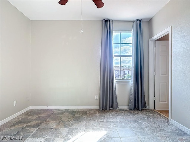 spare room with stone finish flooring, baseboards, and a ceiling fan