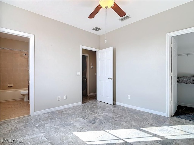 unfurnished bedroom featuring a walk in closet, visible vents, and baseboards