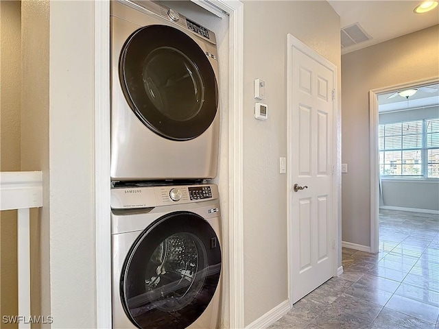 washroom featuring stacked washer / dryer, laundry area, visible vents, and baseboards