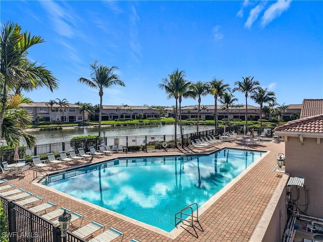 pool featuring a patio area, fence, and a water view