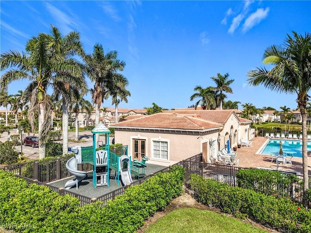 rear view of property featuring a community pool, fence, a patio, and stucco siding