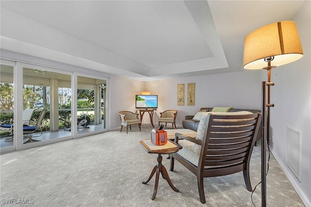 living room featuring visible vents, a raised ceiling, and carpet flooring