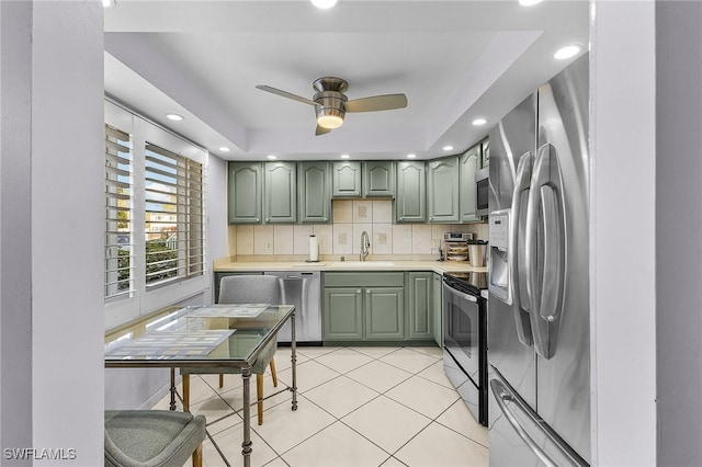 kitchen with light tile patterned floors, green cabinetry, a sink, light countertops, and appliances with stainless steel finishes