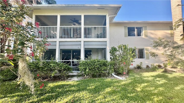 rear view of house featuring a lawn and stucco siding