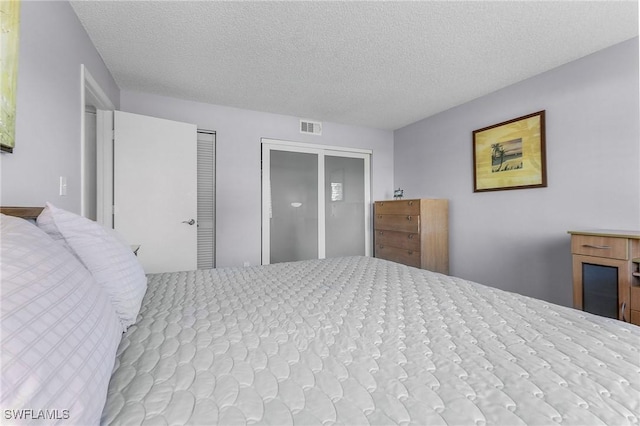 bedroom featuring visible vents, two closets, and a textured ceiling