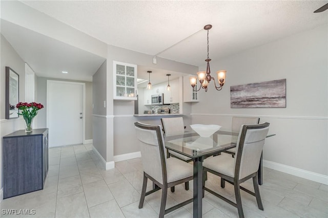 dining room featuring baseboards, a textured ceiling, and a notable chandelier