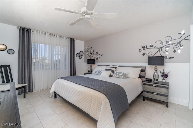 bedroom with a textured ceiling, a ceiling fan, and light tile patterned flooring