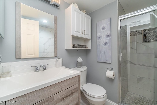 full bathroom featuring a stall shower, vanity, and toilet