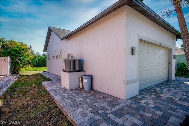 view of home's exterior featuring cooling unit, an attached garage, and stucco siding