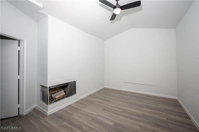 interior space with baseboards, ceiling fan, wood finished floors, vaulted ceiling, and a multi sided fireplace