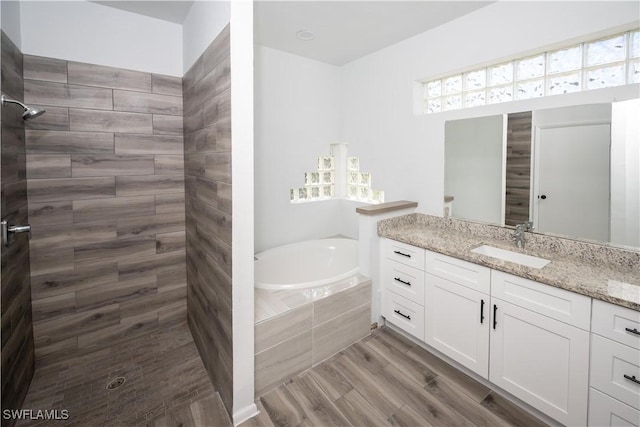 full bathroom with wood finished floors, tiled shower, vanity, and a bath