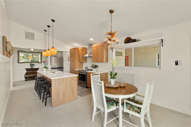 kitchen featuring lofted ceiling, visible vents, light countertops, appliances with stainless steel finishes, and wall chimney exhaust hood