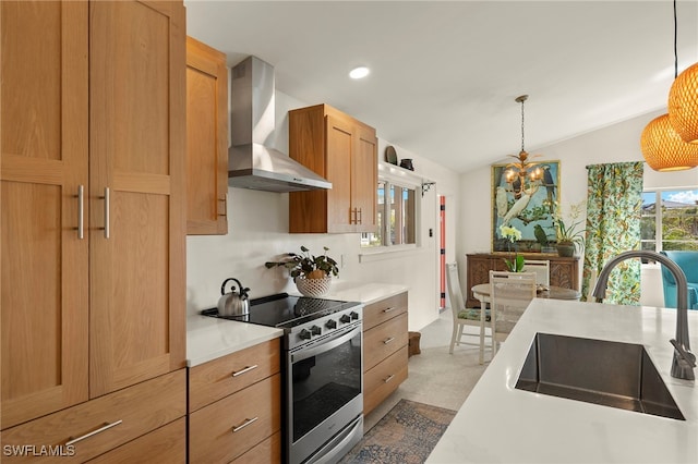 kitchen featuring light countertops, hanging light fixtures, stainless steel range with electric cooktop, a sink, and wall chimney range hood