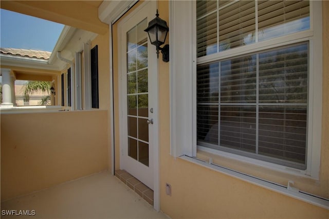 view of exterior entry with a tile roof and stucco siding