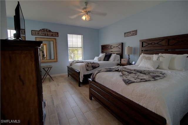 bedroom featuring baseboards, ceiling fan, and light wood-style floors