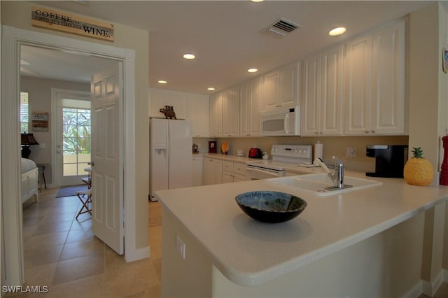 kitchen with recessed lighting, a peninsula, white appliances, a sink, and visible vents