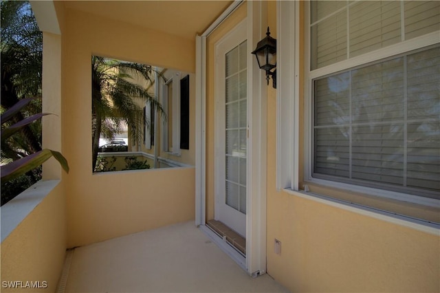 view of exterior entry featuring a balcony and stucco siding