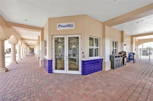 property entrance with fence, stucco siding, and french doors