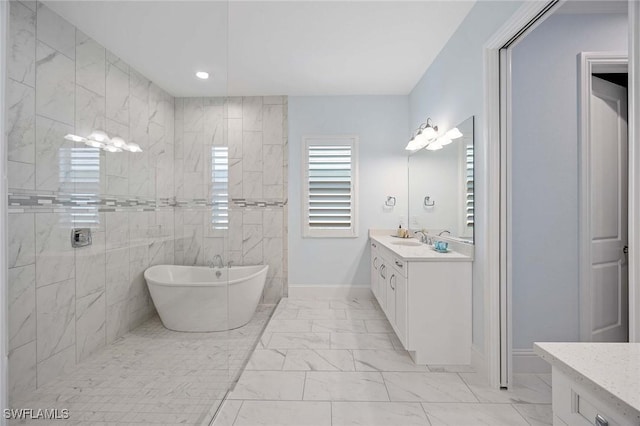 full bath featuring baseboards, a soaking tub, marble finish floor, and vanity