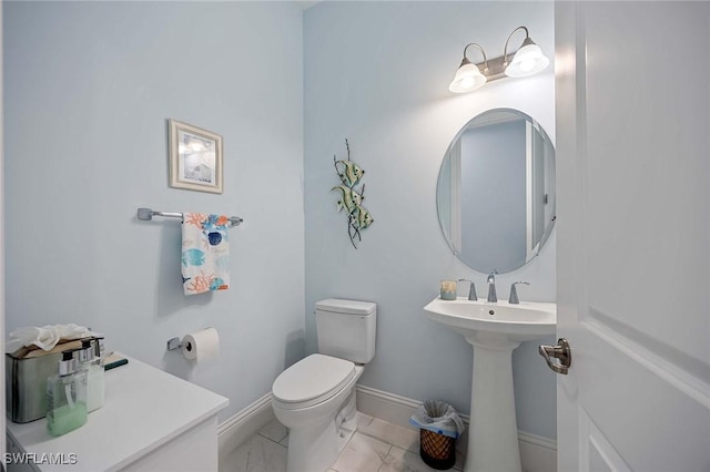 bathroom with marble finish floor, toilet, and baseboards