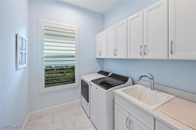 clothes washing area with marble finish floor, a sink, cabinet space, baseboards, and washing machine and clothes dryer