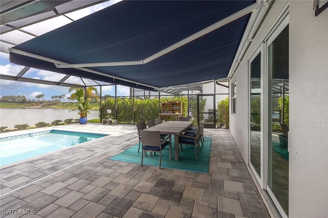 outdoor pool featuring glass enclosure, outdoor dining area, a patio area, and a water view