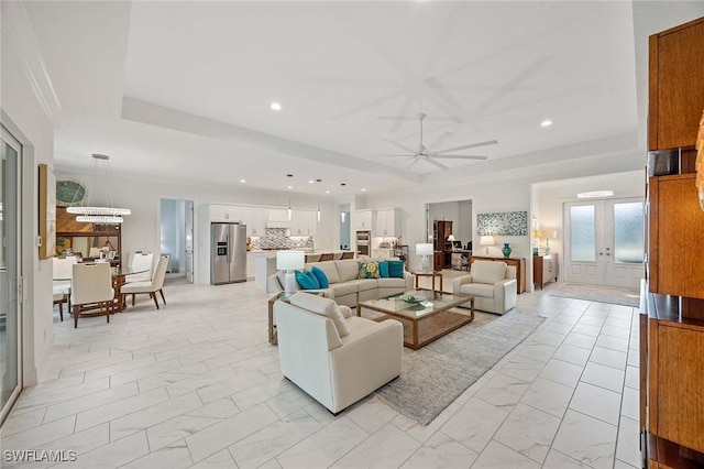 living area with a ceiling fan, a tray ceiling, recessed lighting, french doors, and marble finish floor