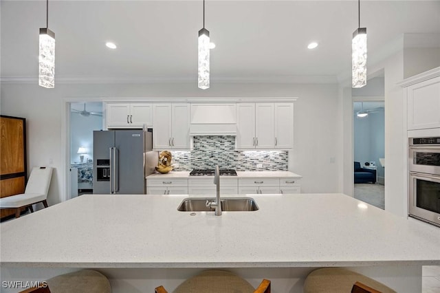 kitchen featuring backsplash, a breakfast bar area, custom range hood, stainless steel appliances, and a sink