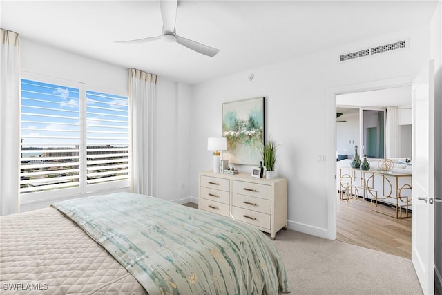 bedroom with a ceiling fan, light colored carpet, visible vents, and baseboards