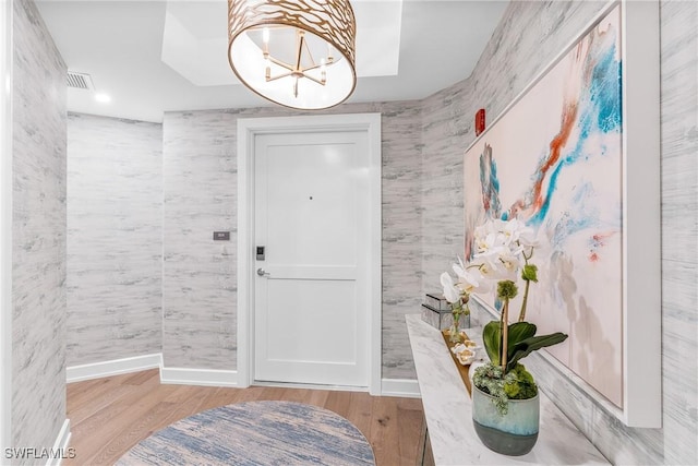 entryway with an inviting chandelier, visible vents, baseboards, and wood finished floors