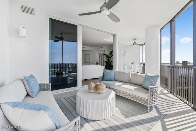 living area with a wall of windows, visible vents, and a ceiling fan